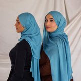 Two models styled in bright blue hijabs against a plain background
