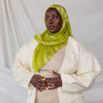 Model styled in a lime green sediment printed hijab and white outfit against a plain background