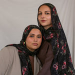 Two models wearing black pomegranate printed hijabs against a plain background