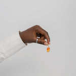 Hand holding a small mango shaped gemstone against a plain background