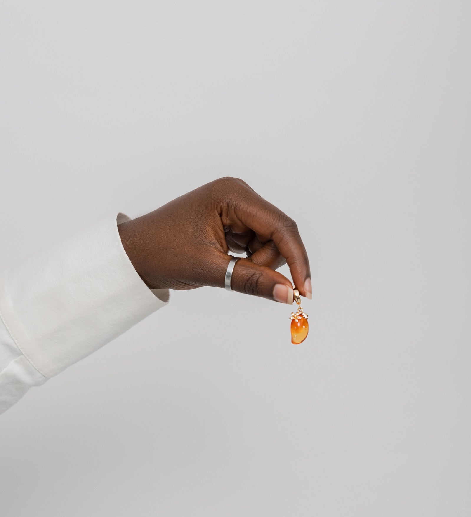 Hand holding a small mango shaped gemstone against a plain background