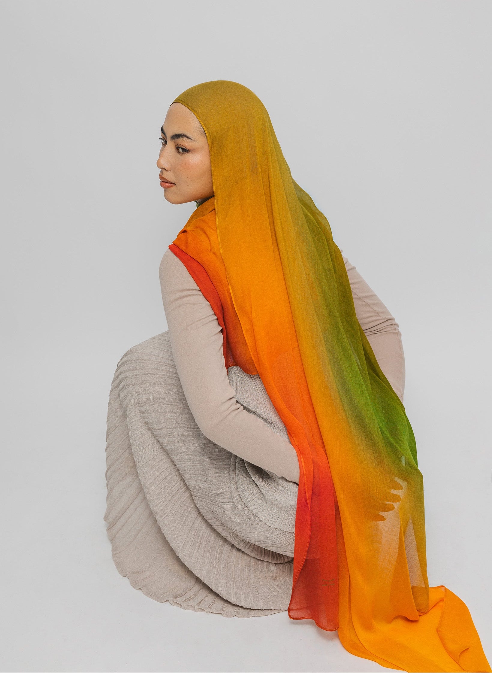 Person wearing a mango hijab with an ombre effect on a plain background