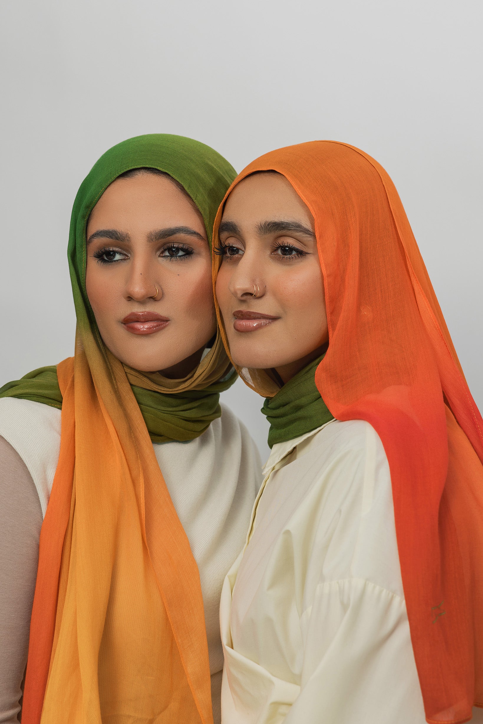 Two women wearing mango ombre hijabs against a plain background