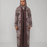 Woman wearing a long floral dress with a brown hijab on a gray background