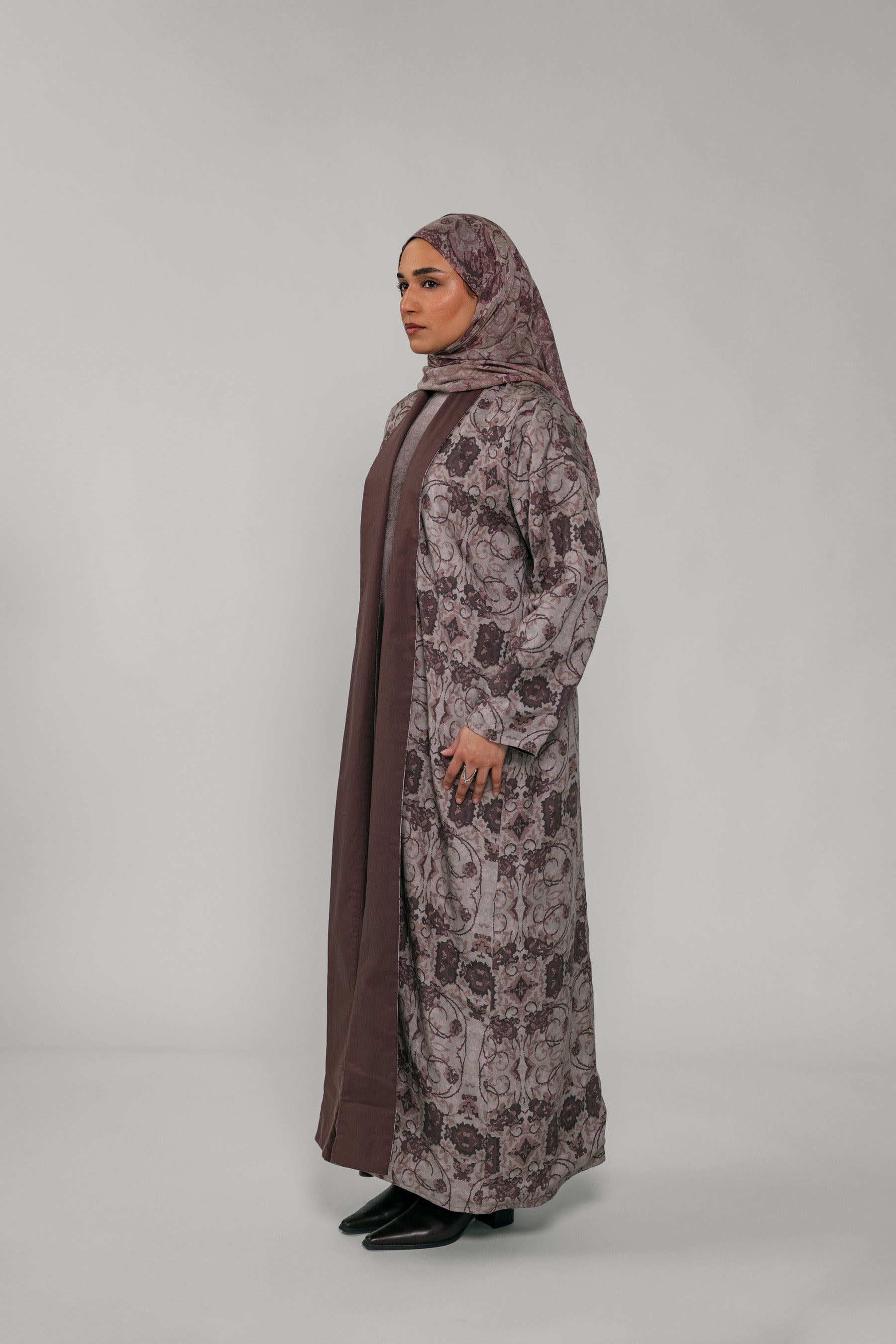 Woman wearing a floral abaya and hijab on a gray background