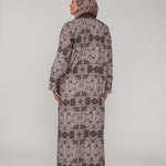Woman wearing a long floral-patterned abaya and hijab on a gray background