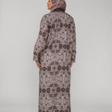 Woman wearing a long floral-patterned abaya and hijab on a gray background