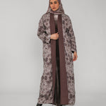 Woman wearing a long floral abaya with a brown floral hijab on a gray background