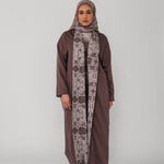 Woman wearing a brown abaya and patterned hijab on a gray background