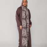 Woman wearing a long brown dress with a floral patterned scarf on a white background