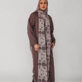 Woman wearing a long brown dress with a floral patterned scarf on a white background