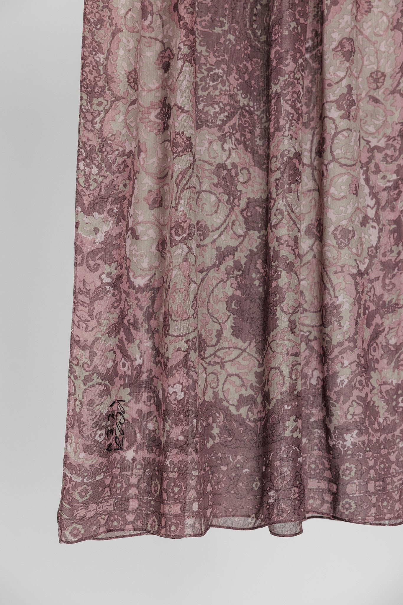 Close-up of hijab fabric with a mauve floral pattern on a white background