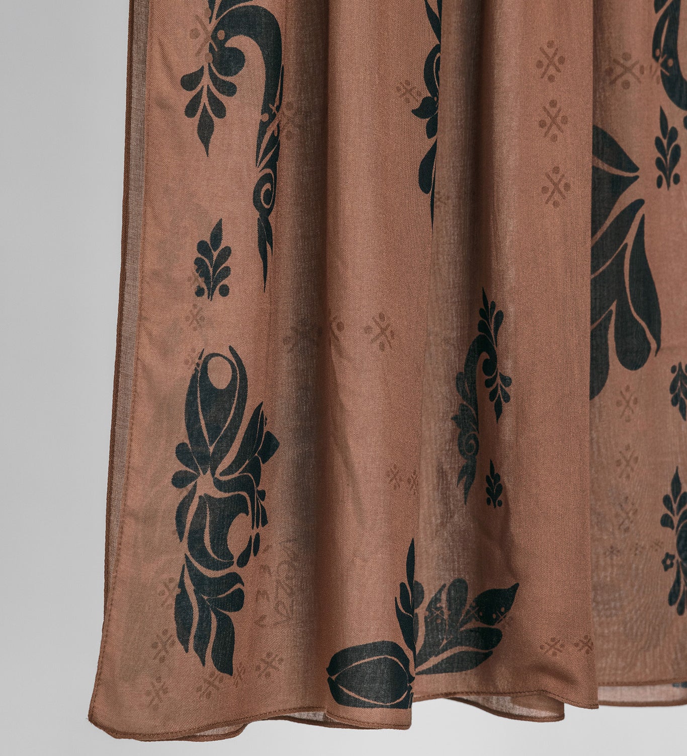 Brown hijab fabric with black floral patterns on a white background