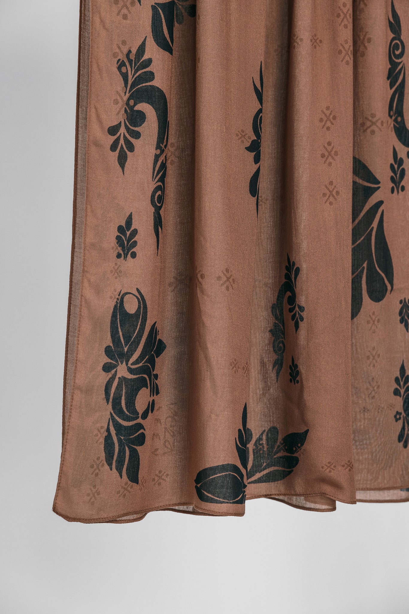 Brown hijab fabric with black floral patterns on a white background