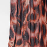 A close-up of a pleated fabric garment, likely a skirt, featuring an abstract animal-inspired print in shades of rust orange, brown, and charcoal gray.