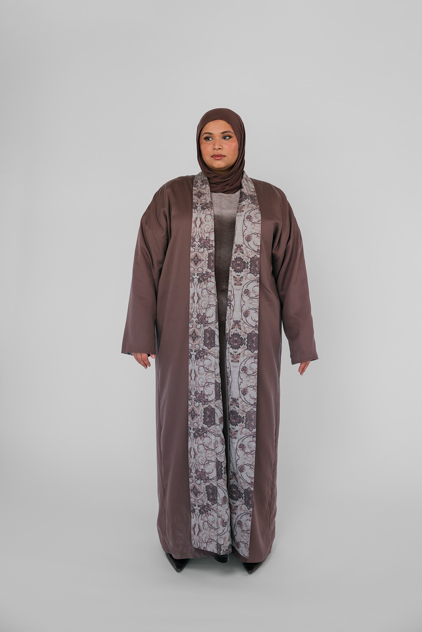 Woman wearing a long abaya with a hijab on a white background