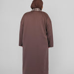 Person wearing a long brown abaya and hijab on a white background