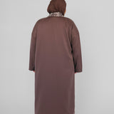 Person wearing a long brown abaya and hijab on a white background