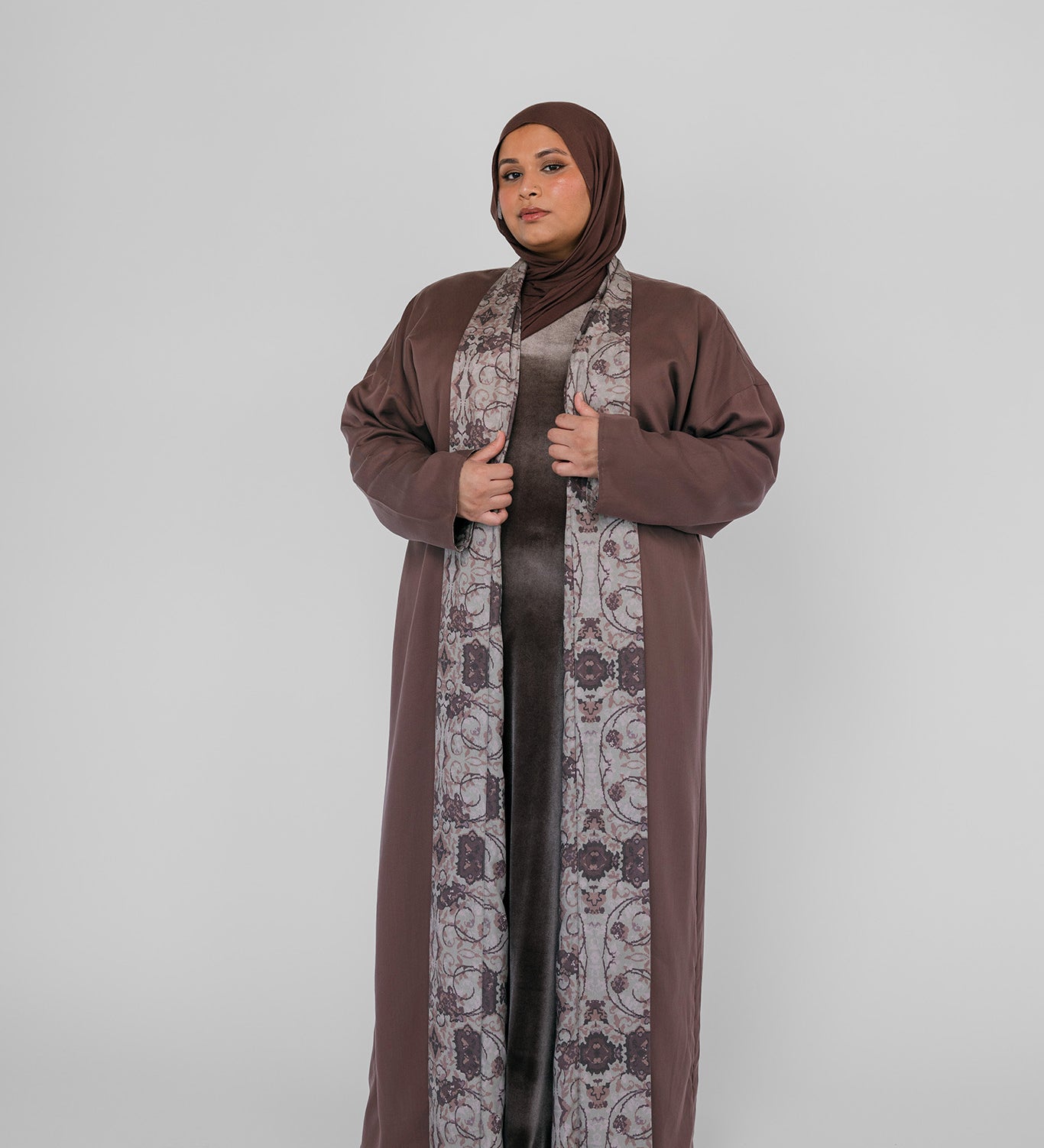 Woman wearing a brown abaya with a hijab on a white background