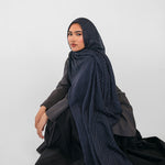 Woman wearing a dark blue hijab and black outfit on a white background