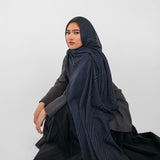 Woman wearing a dark blue hijab and black outfit on a white background