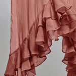 A close-up of a nectar pink ruffled fabric, showing the layered, cascading texture of the material against a neutral gray background.