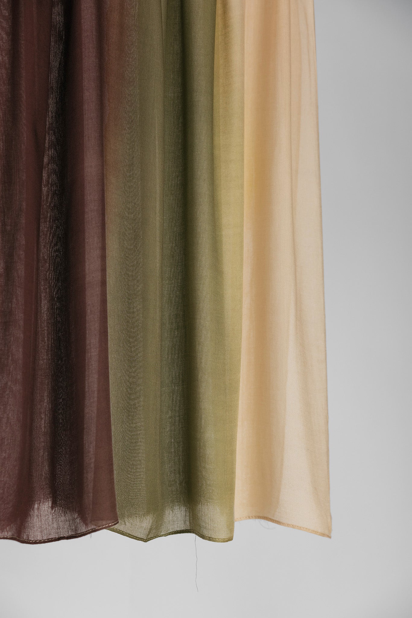 Hijab fabric swatch in brown, green, and beige ombre on a plain background