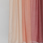 Hijab fabric swatch with gradient color from light pink to red on a plain background