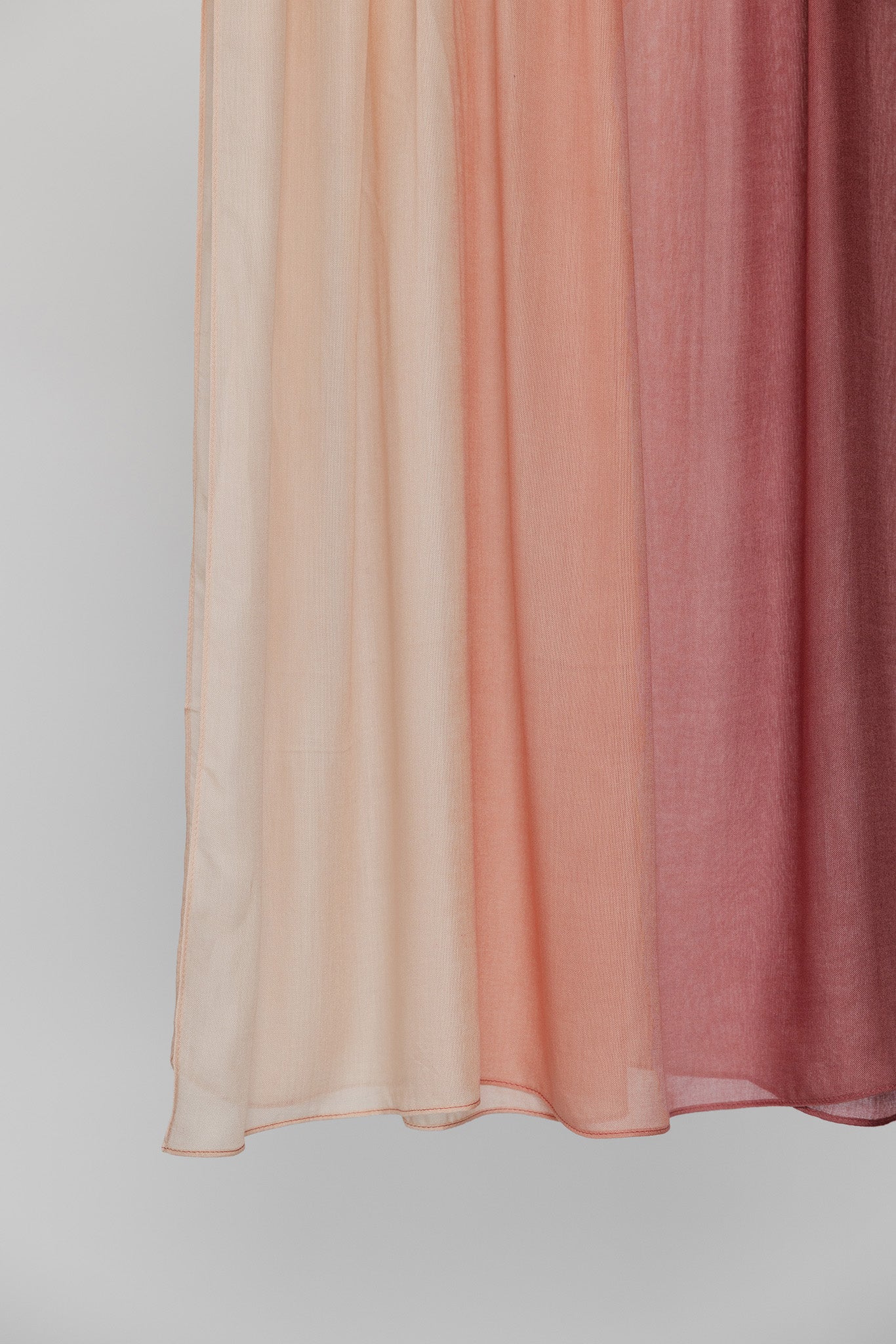 Hijab fabric swatch with gradient color from light pink to red on a plain background