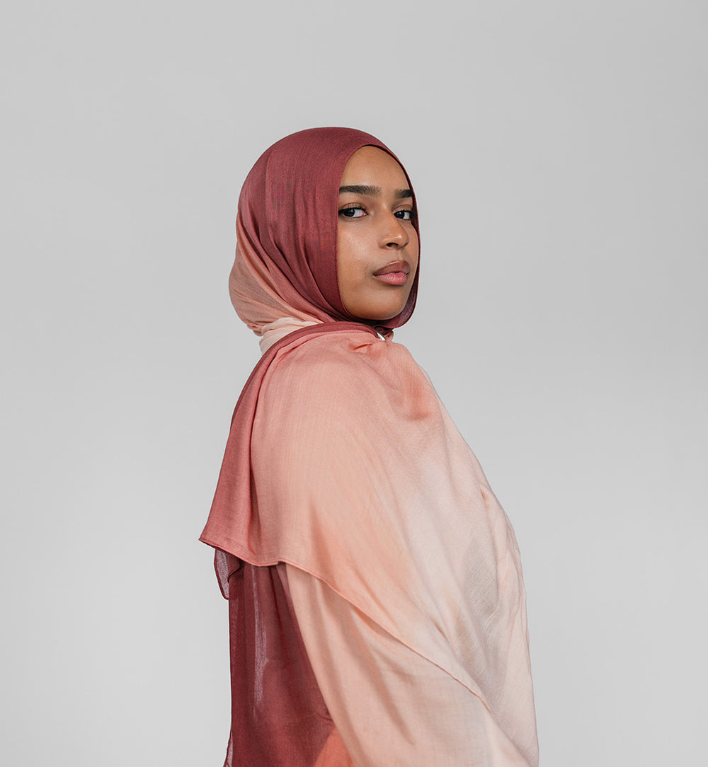 Woman wearing a gradient hijab in pink and brown on a plain background