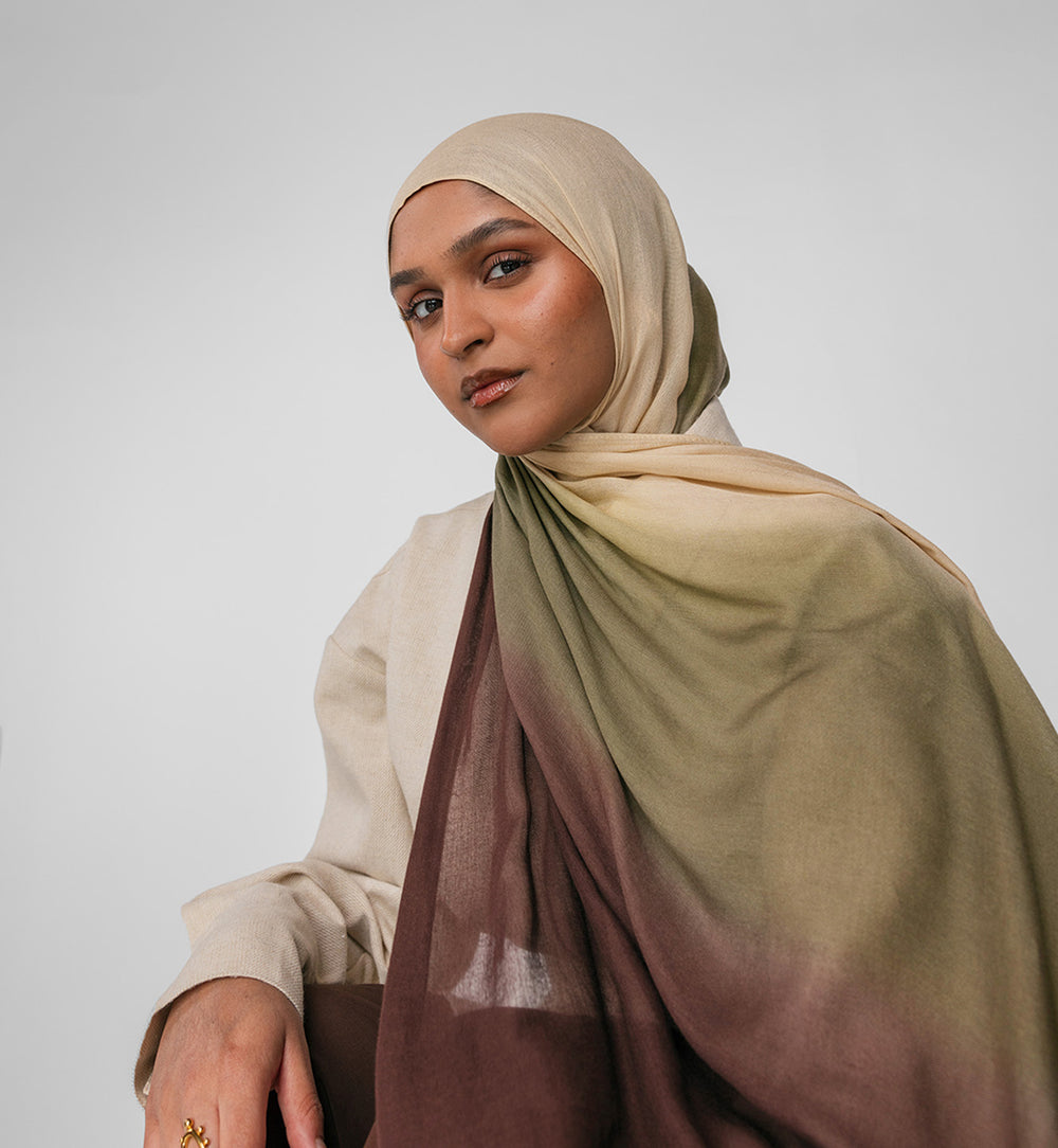 Woman wearing a beige hijab with gradient colors on a plain background
