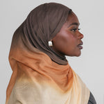 Woman wearing a ombre gradient hijab in brown, orange, and beige on a plain background