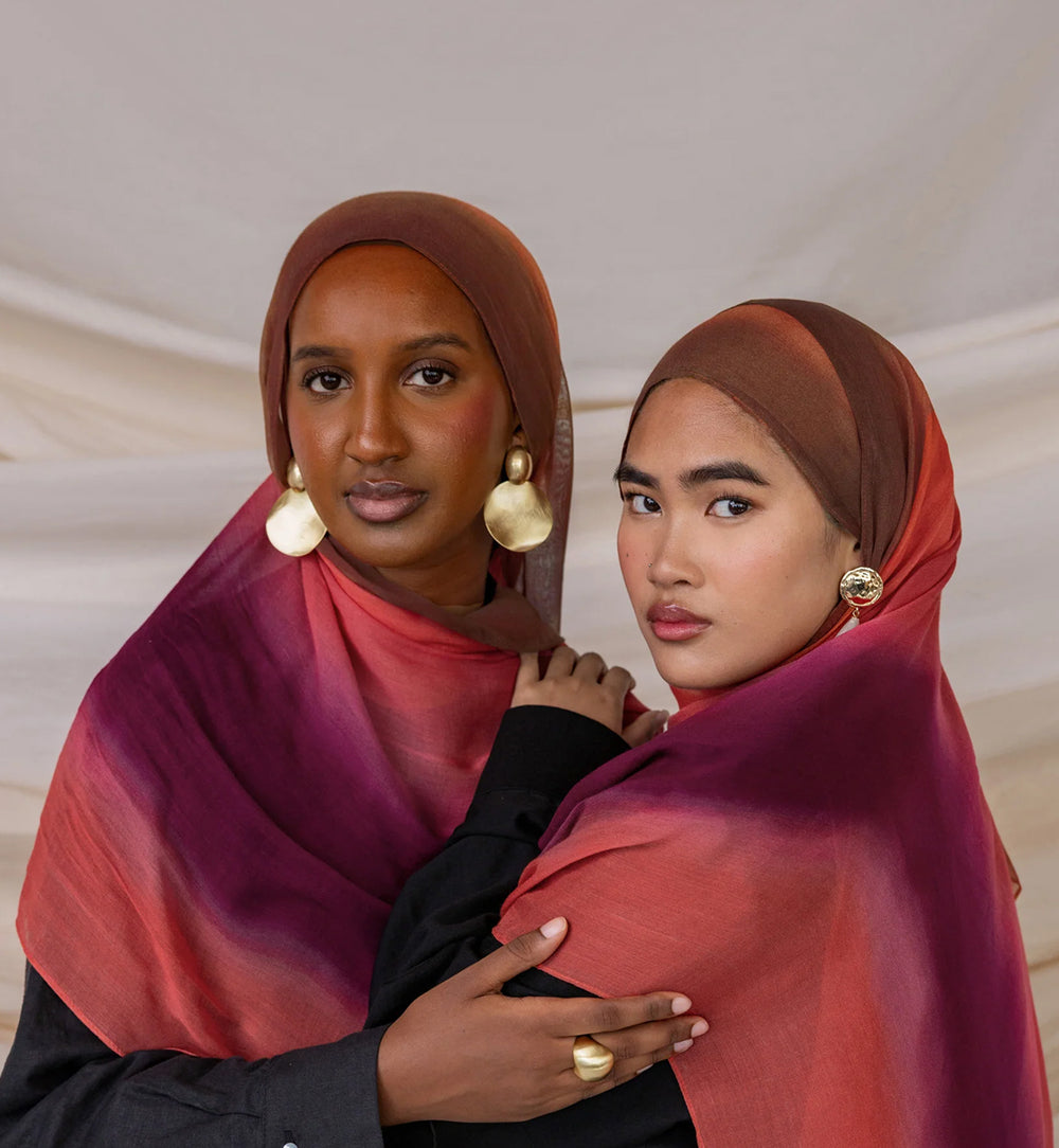 Two women wearing hijabs with a neutral background