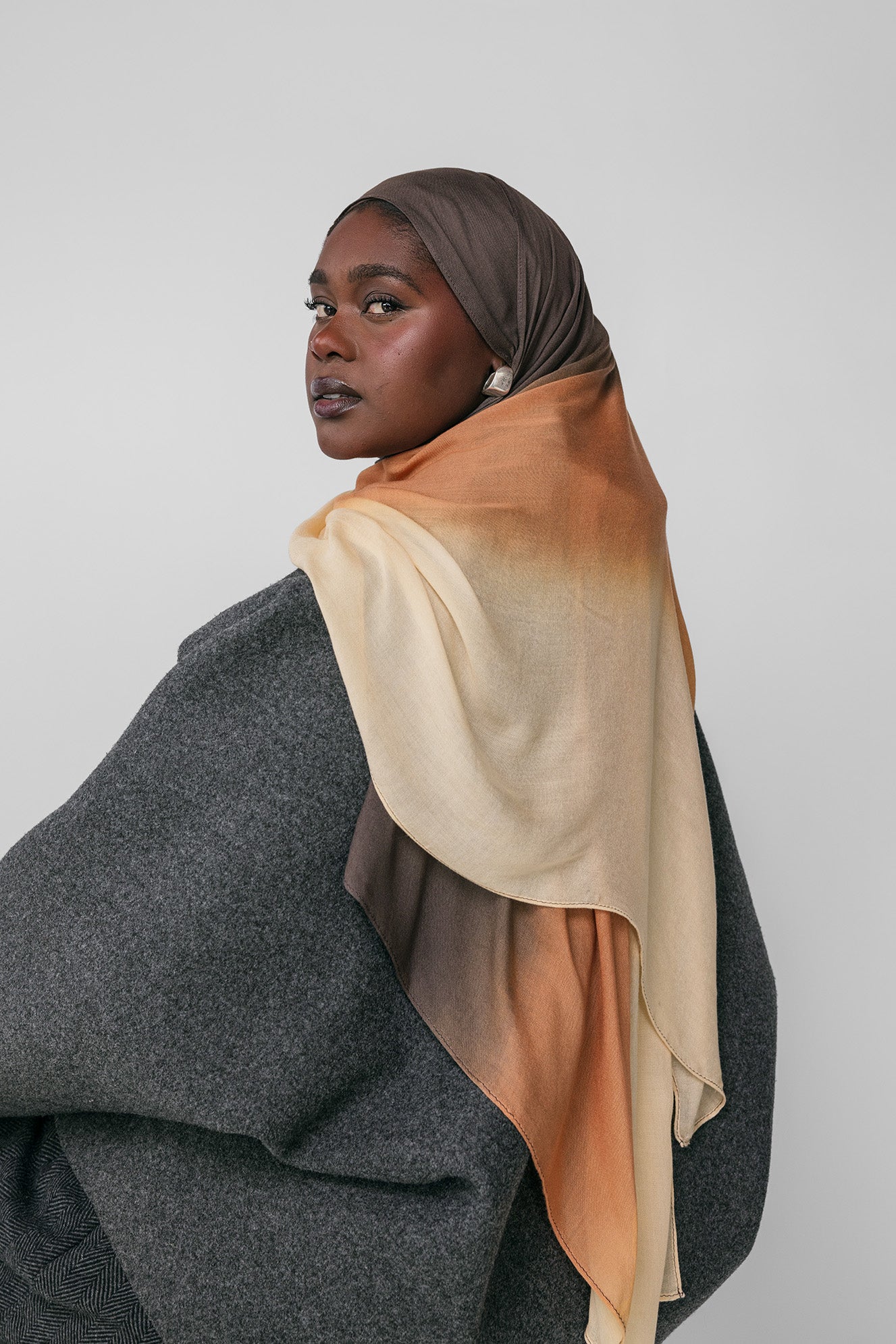 Woman wearing a ombre gradient hijab with a plain background
