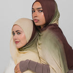 Two women wearing hijabs in beige and brown on a plain background