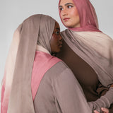 Two women wearing pink and beige ombre hijabs in a neutral setting