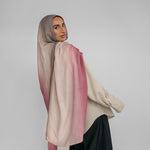 Woman wearing a pink and beige ombre hijab against a plain background