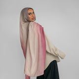 Woman wearing a pink and beige ombre hijab against a plain background