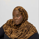 Person wearing a ocelot print hijab and black outfit on a white background