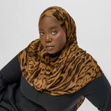 Person wearing a  ocelot print hijab and black outfit on a white background