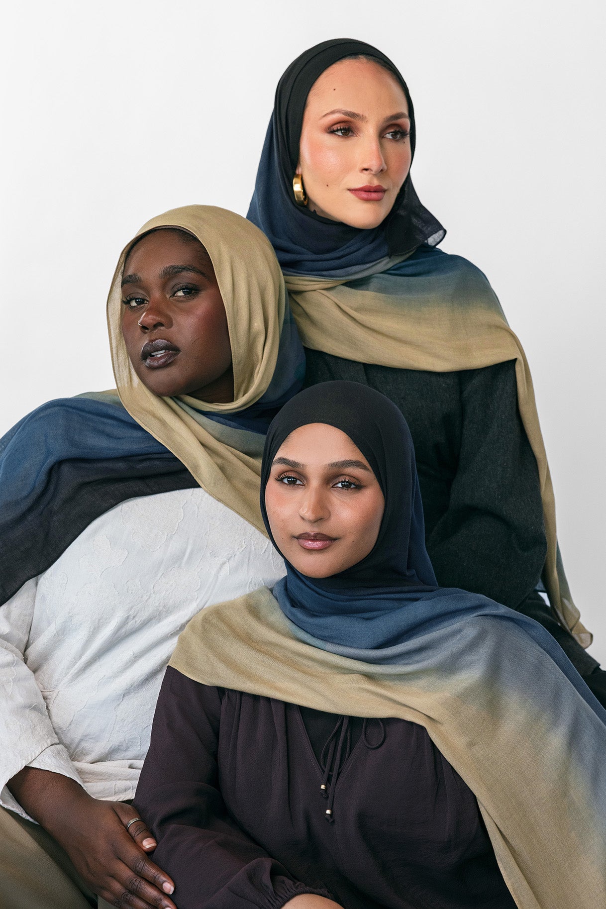 Three women wearing blue ombre hijabs in various colors on a white background