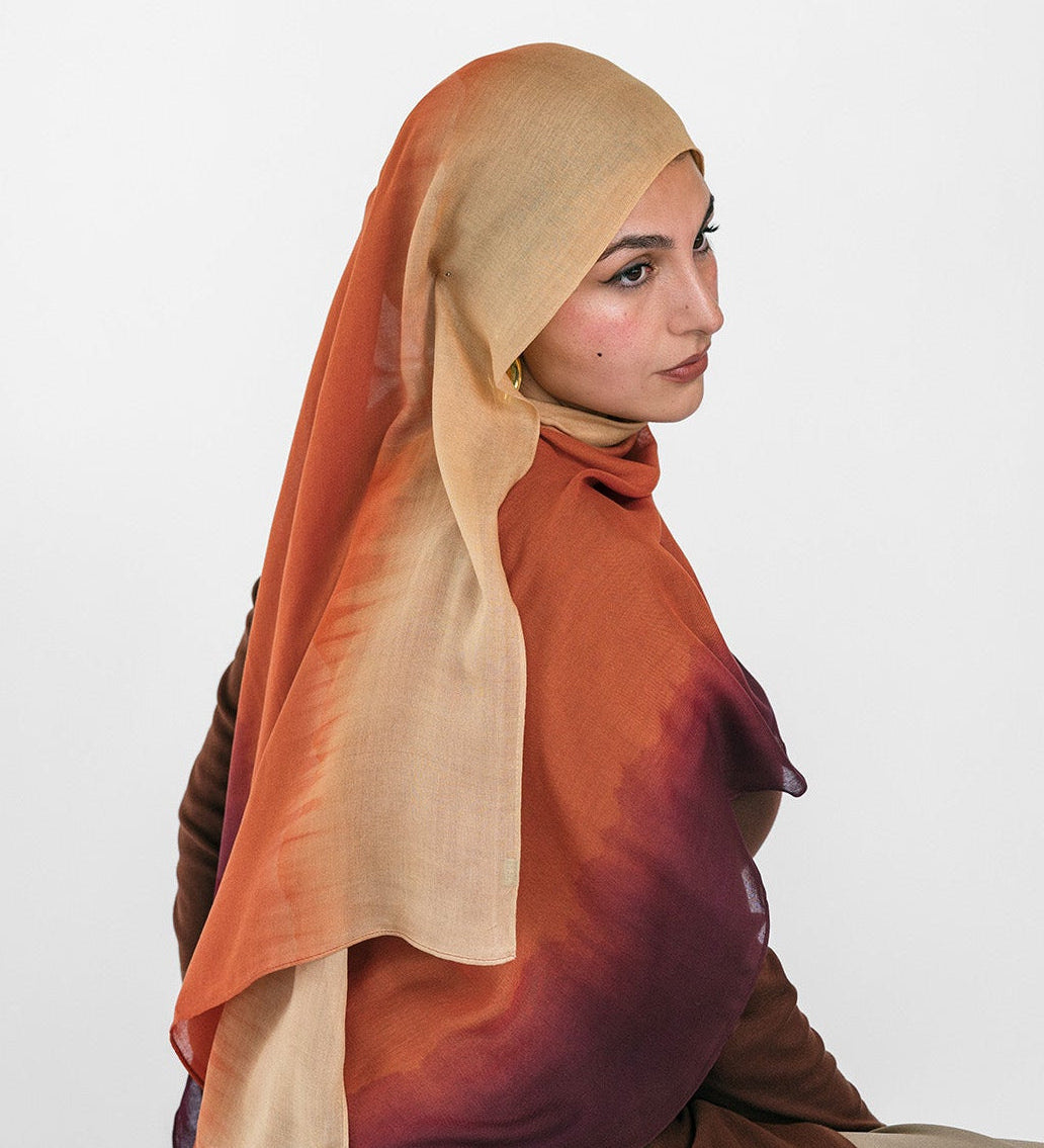 Woman wearing a brown and beige ombre hijab sitting on a white background