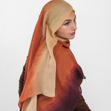 Woman wearing a brown and beige ombre hijab sitting on a white background
