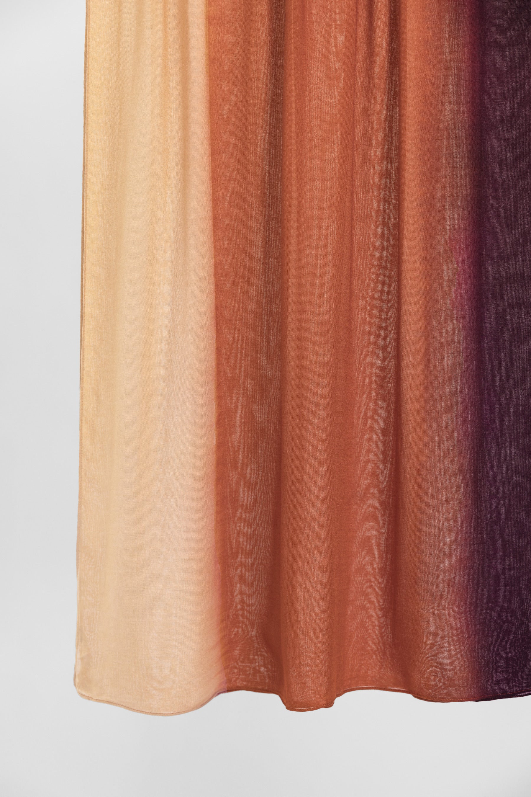 Ombre fabric swatch with colors transitioning from beige to brown to purple on a light gray background.