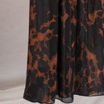 Black, brown, orange tortoiseshell patterned fabric on a plain background