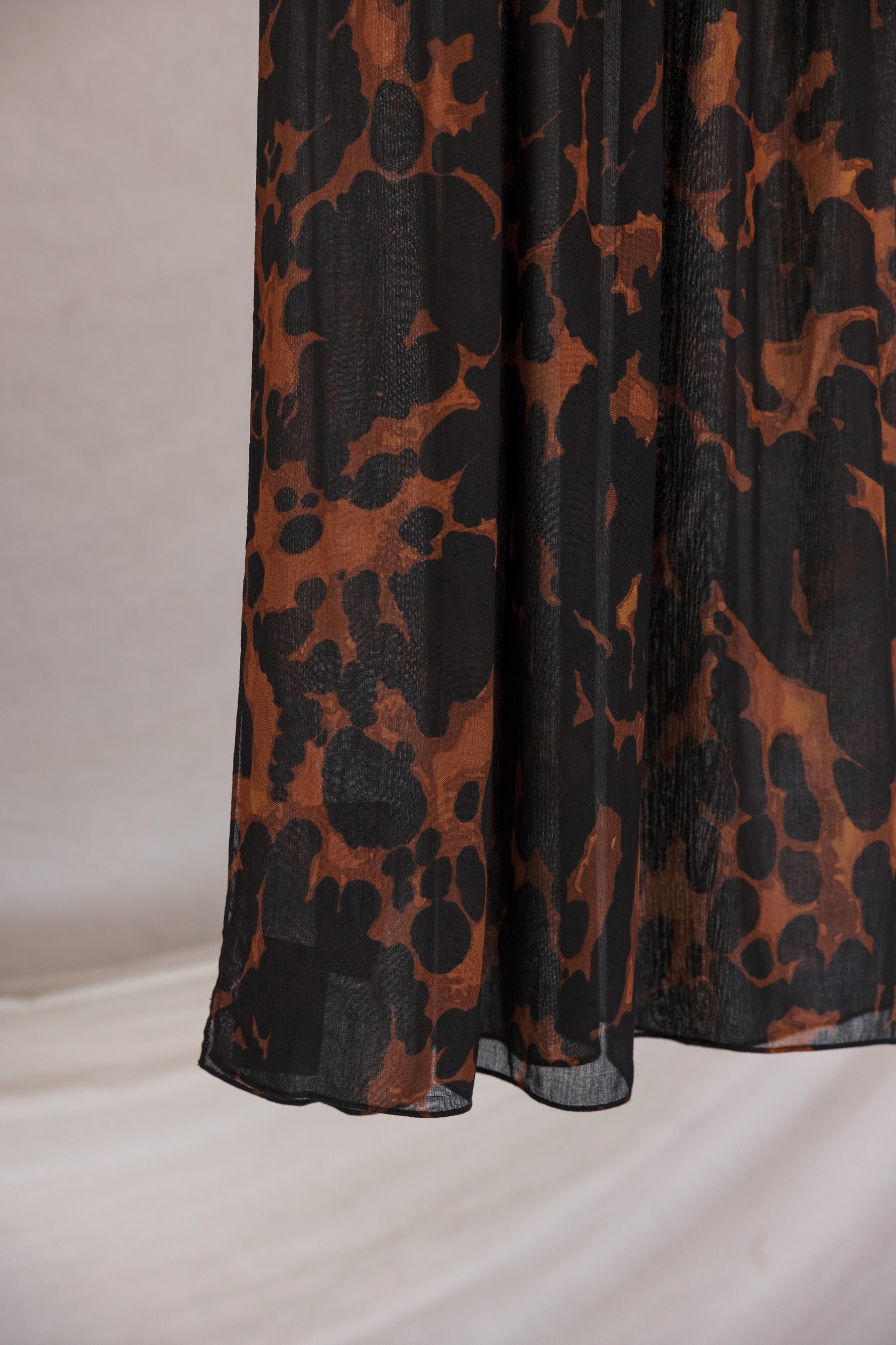 Black, brown, orange tortoiseshell patterned fabric on a plain background