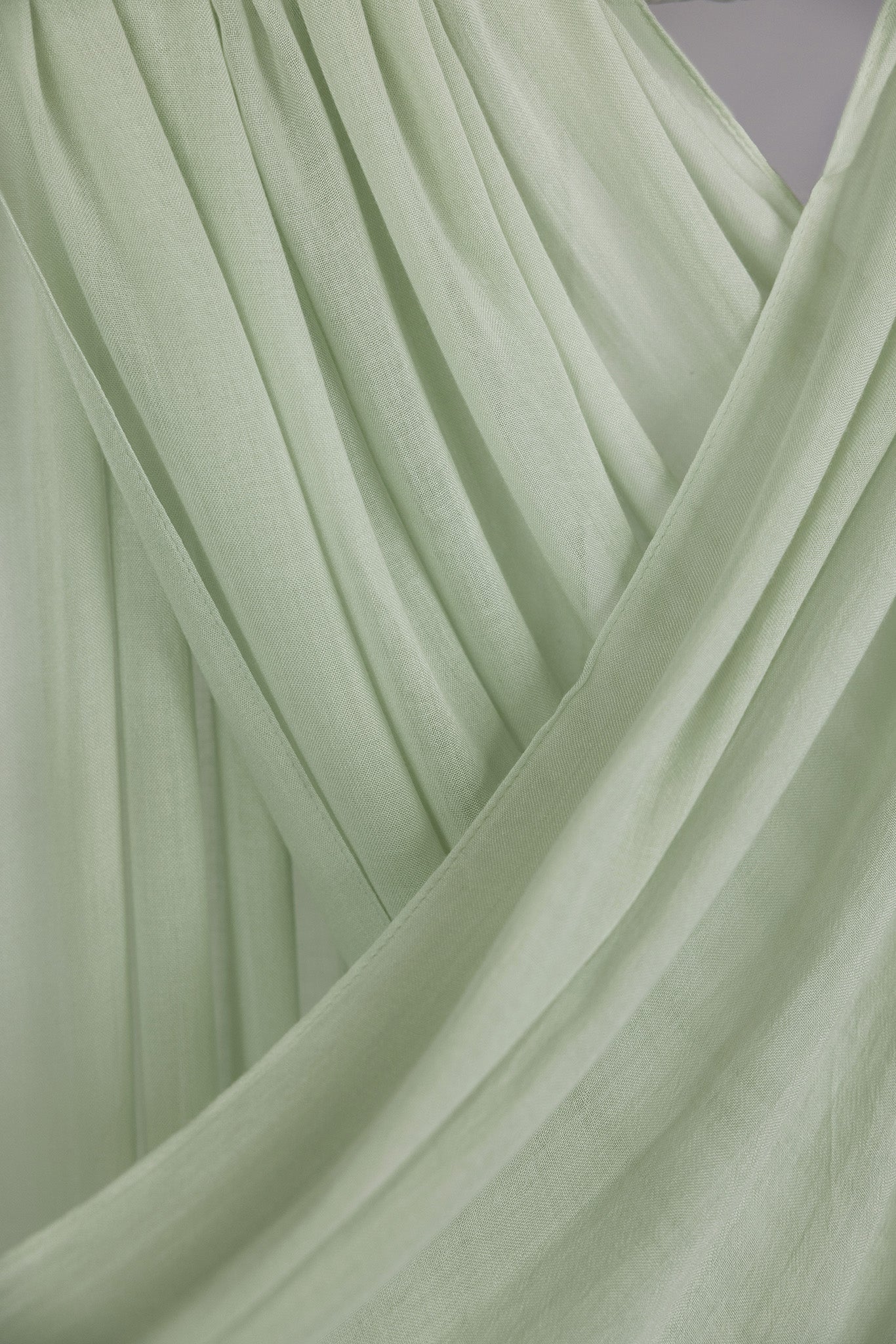 Close-up of light pastel green hijab with folded draping against backdrop