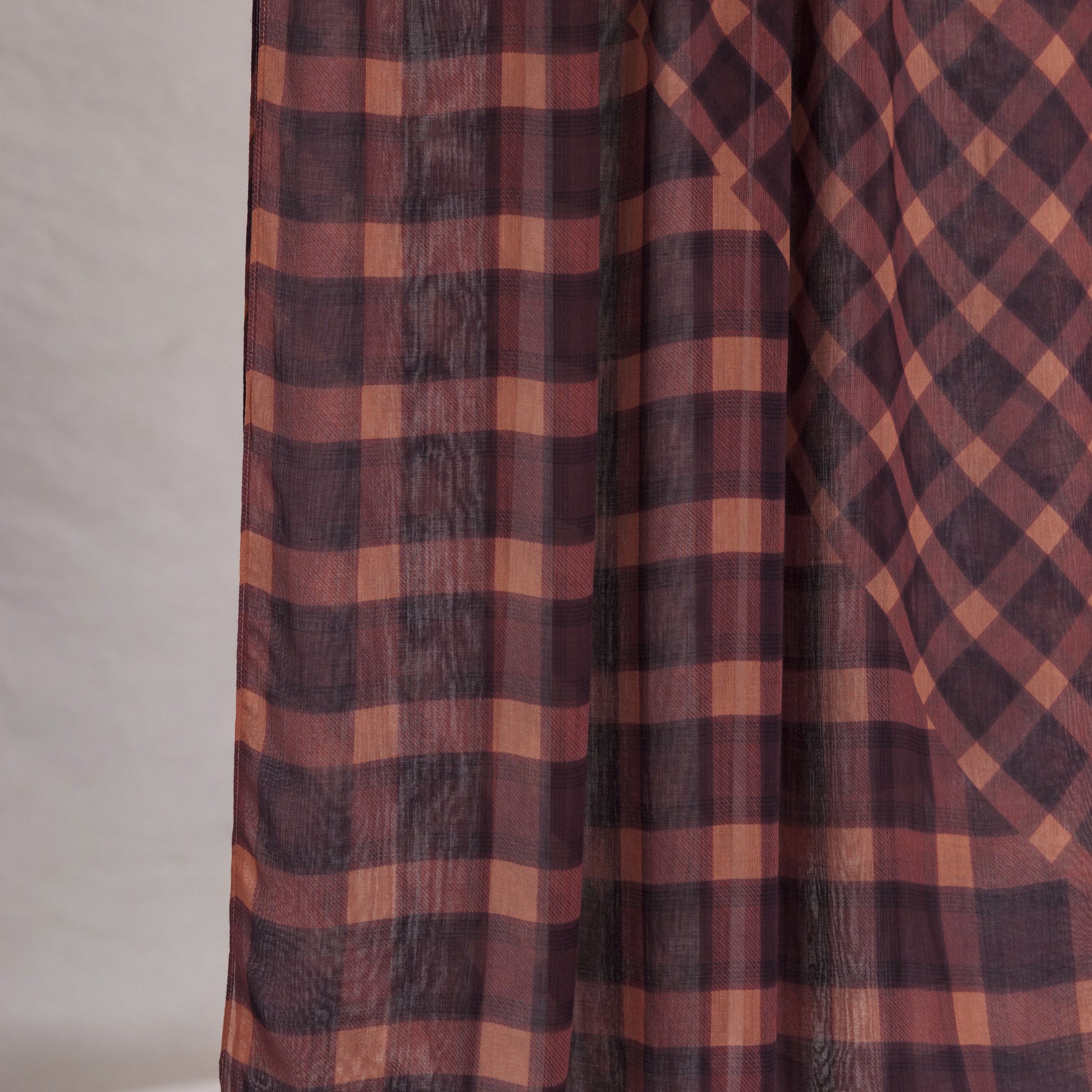 Plaid fabric with brown and red pattern on a neutral background