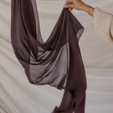 Brown chiffon hijab being held against a neutral background