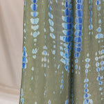 Green hijab with blue and white ripple pattern on a beige background